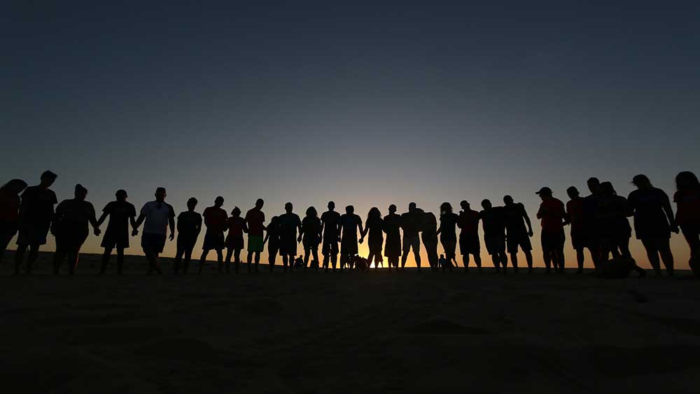 A line of people together at dusk